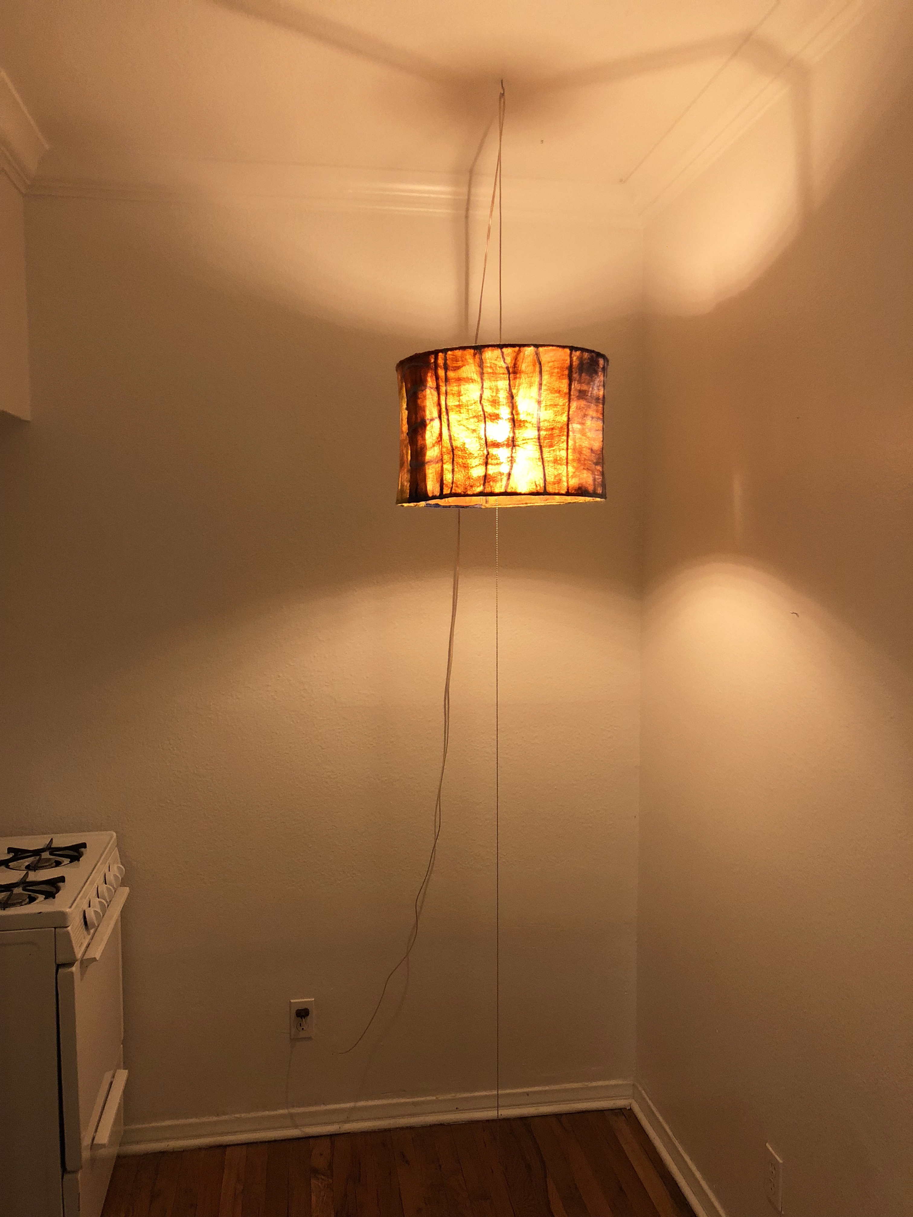 A felt lamp hanging from the ceiling of a kitchen emitting warm light